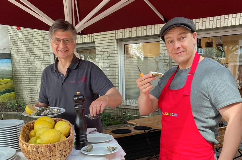 Zwei Männer an einem Buffet mit Auster in der Hand