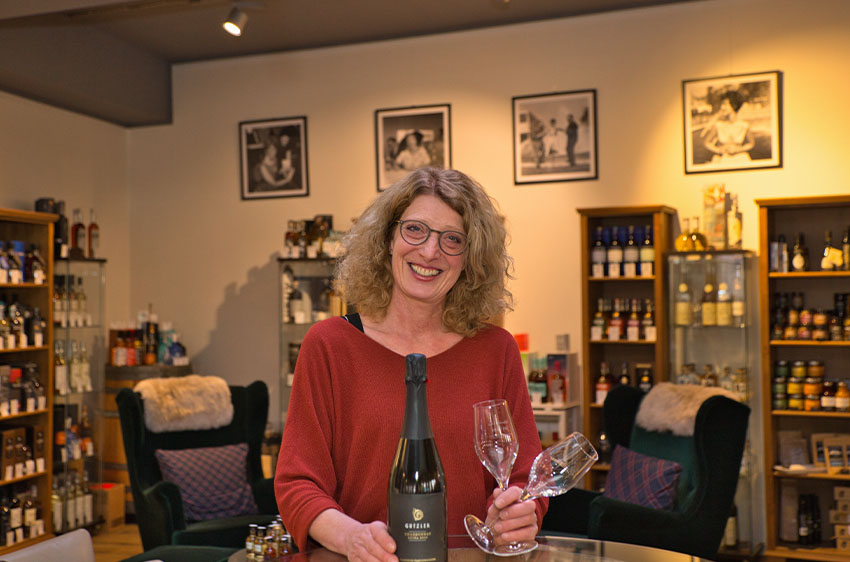 Eine Frau hält in der Whiskyecke eine Flasche Wein und zwei Gläser in den Händen